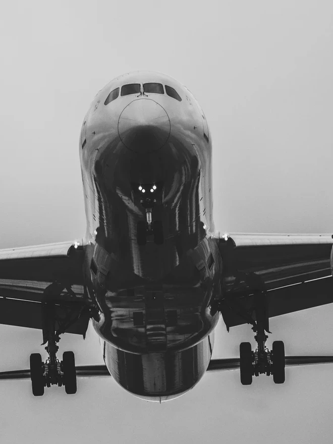 A commercial airliner viewed head-on against an overcast sky.