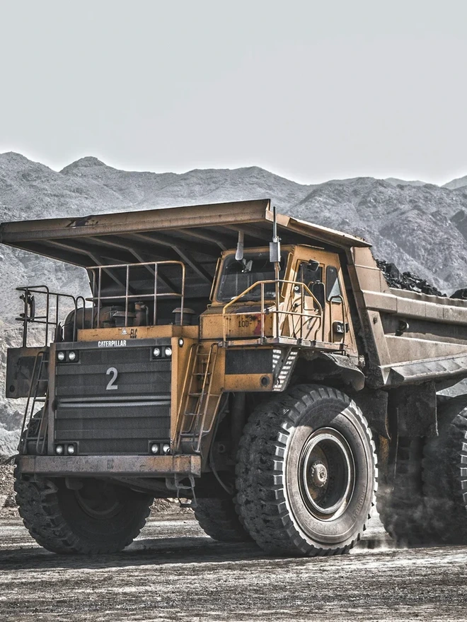 A large mining haul truck on a mine haul road below mountains.